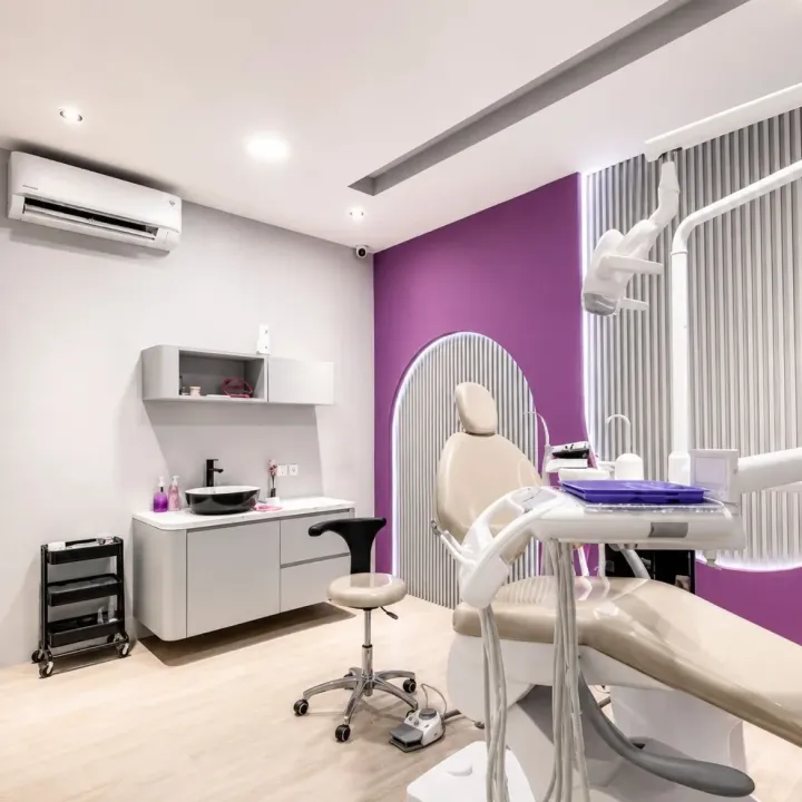 Ruang tindakan Rata Dental dengan kursi dental krem dan panel lengkung bercahaya